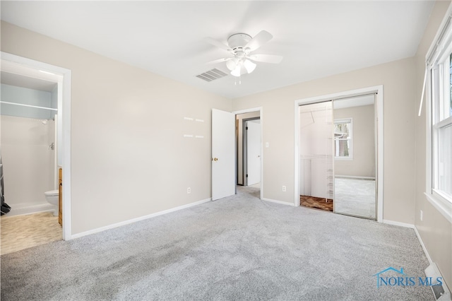 unfurnished bedroom with connected bathroom, light colored carpet, a closet, and ceiling fan