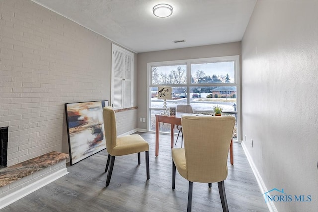 living area featuring hardwood / wood-style flooring and brick wall