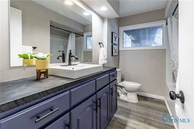 full bathroom with vanity, hardwood / wood-style flooring, toilet, and shower / bathtub combination with curtain