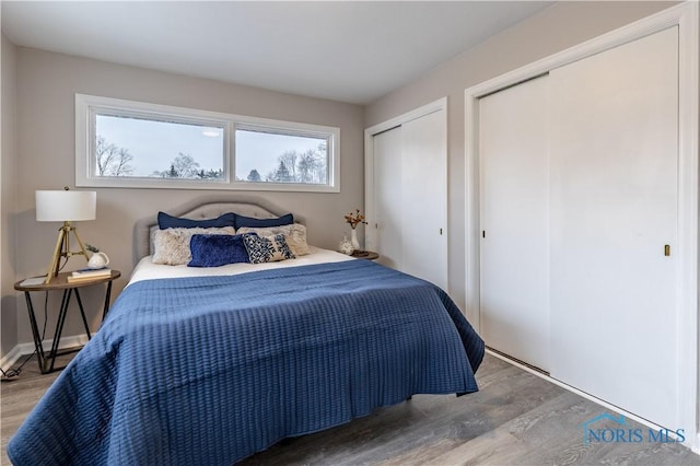 bedroom featuring wood-type flooring and multiple closets