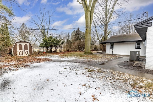 yard layered in snow with central AC and a storage unit