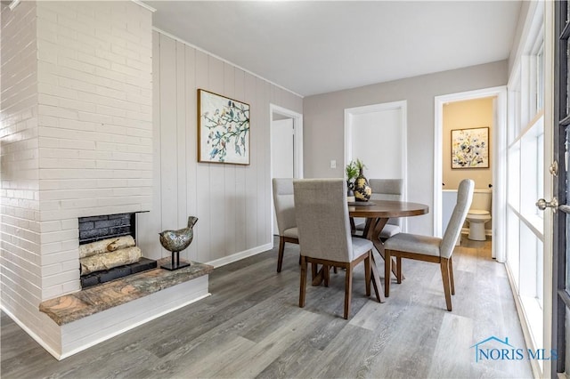 dining room featuring a large fireplace and wood-type flooring