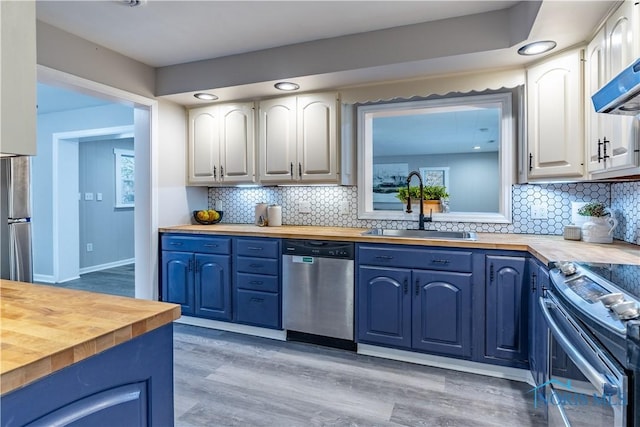 kitchen with stainless steel appliances, sink, butcher block countertops, and white cabinets