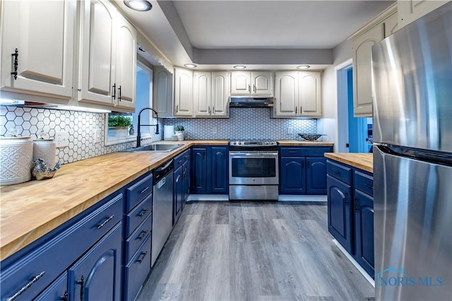 kitchen with butcher block countertops, sink, white cabinetry, stainless steel appliances, and blue cabinets