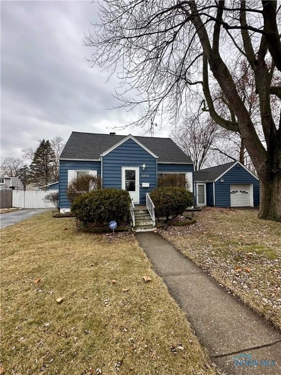 view of front facade featuring an outbuilding, a garage, and a front lawn