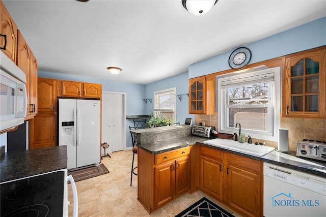 kitchen with sink, white appliances, kitchen peninsula, and decorative backsplash