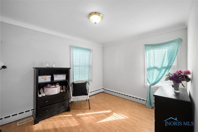 sitting room featuring wood-type flooring and a baseboard heating unit