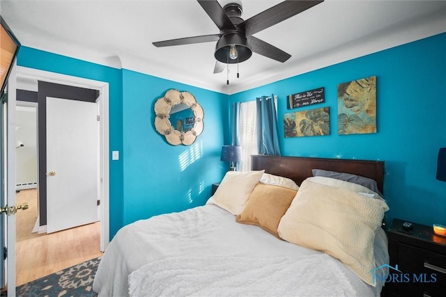 bedroom featuring hardwood / wood-style floors, a baseboard radiator, and ceiling fan