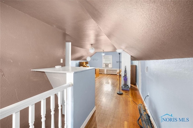 hall featuring lofted ceiling, a textured ceiling, and light wood-type flooring