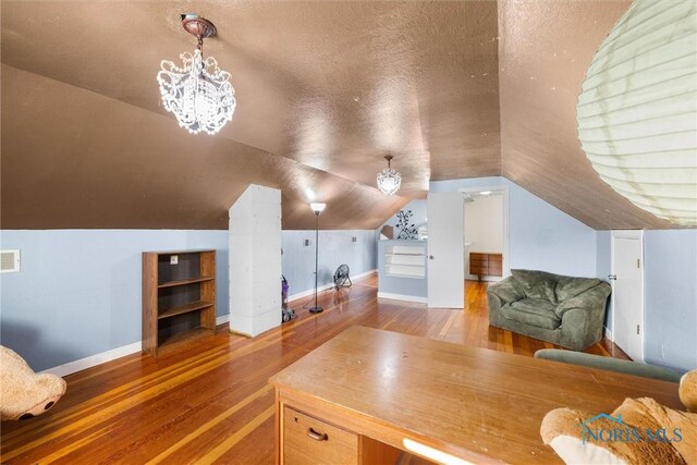 office featuring hardwood / wood-style flooring, lofted ceiling, a textured ceiling, and a notable chandelier