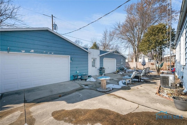 ranch-style home with central AC unit, a garage, and an outdoor structure