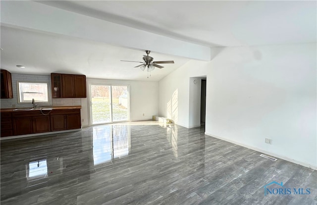 unfurnished living room featuring sink, lofted ceiling with beams, dark hardwood / wood-style floors, and ceiling fan