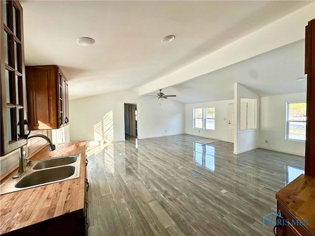 kitchen with sink, dark wood-type flooring, vaulted ceiling with beams, and ceiling fan