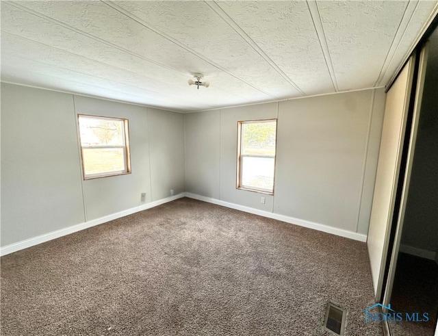 empty room featuring a textured ceiling, carpet floors, and a healthy amount of sunlight