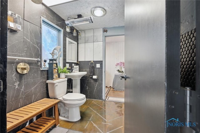 bathroom with sink, tile walls, a textured ceiling, tile patterned floors, and toilet