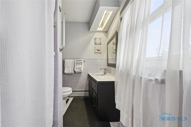 bathroom with tile walls, vanity, toilet, and a shower with shower curtain