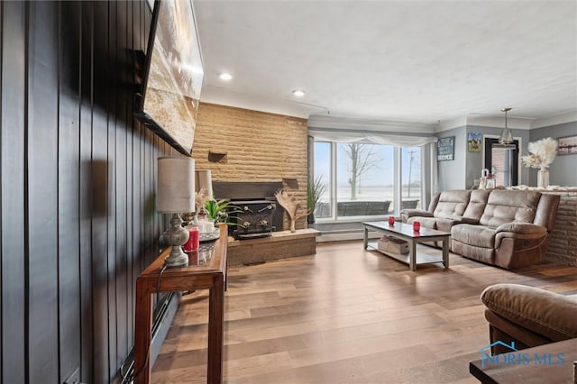 living room featuring a large fireplace, a baseboard radiator, and hardwood / wood-style floors