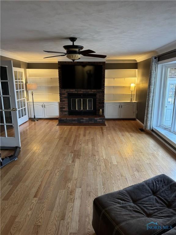 unfurnished living room featuring ceiling fan, a fireplace, and light hardwood / wood-style floors