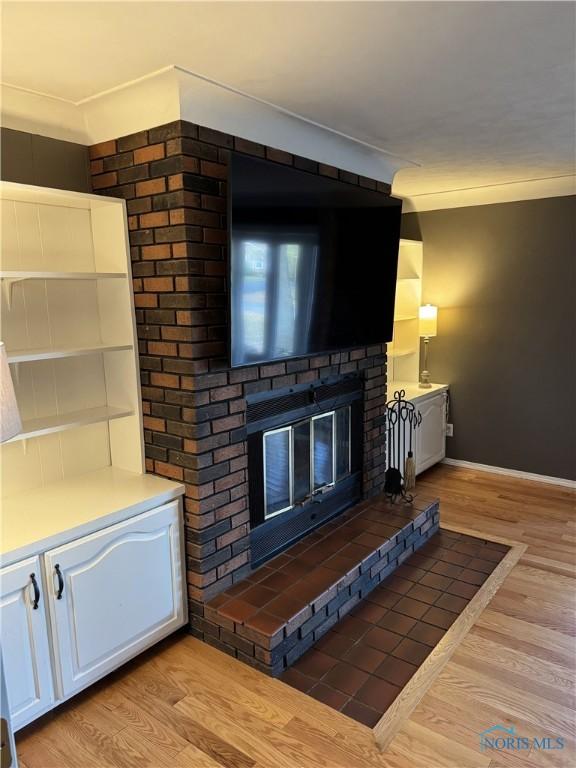 living room with ornamental molding, a fireplace, and light hardwood / wood-style floors