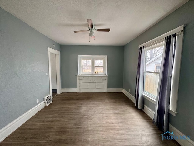 spare room featuring wood-type flooring, a textured ceiling, and plenty of natural light