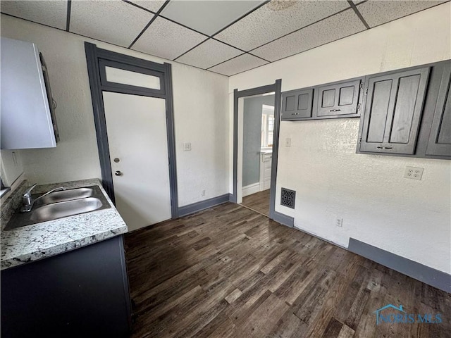 kitchen with gray cabinets, sink, a drop ceiling, and dark hardwood / wood-style flooring