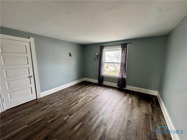 unfurnished room with dark wood-type flooring and a textured ceiling