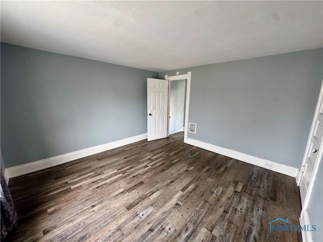 empty room featuring dark hardwood / wood-style flooring and a textured ceiling