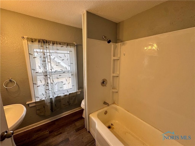 bathroom featuring toilet, bathtub / shower combination, hardwood / wood-style floors, and a textured ceiling