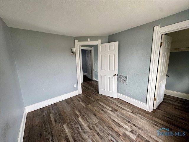 unfurnished bedroom featuring dark hardwood / wood-style flooring, a spacious closet, and a closet