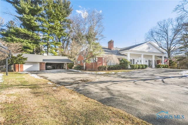 view of front of home with a garage, covered porch, and a front yard