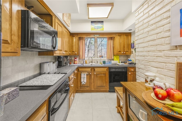 kitchen featuring light tile patterned flooring, brick wall, sink, backsplash, and black appliances