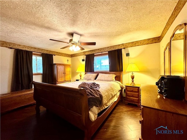 bedroom with multiple windows, ceiling fan, dark wood-type flooring, and a textured ceiling