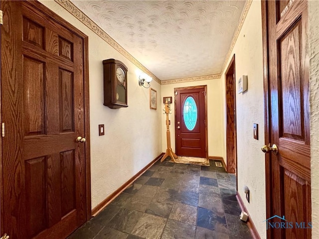 entryway with ornamental molding and a textured ceiling