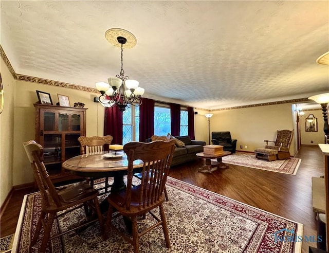 dining space featuring dark hardwood / wood-style floors, a notable chandelier, and a textured ceiling