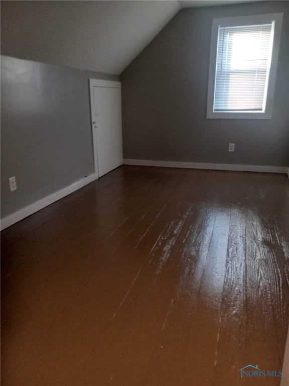 bonus room featuring vaulted ceiling and dark wood-type flooring