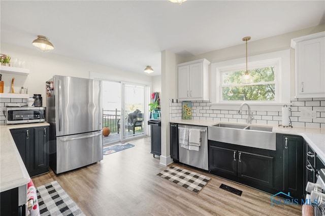 kitchen with white cabinetry, stainless steel appliances, sink, and pendant lighting