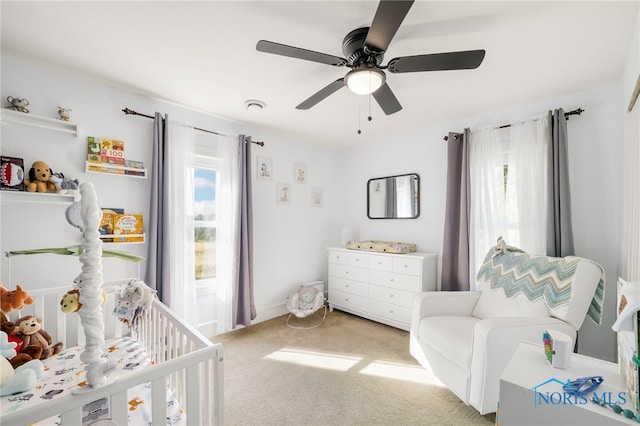 bedroom with ceiling fan, light carpet, and a crib