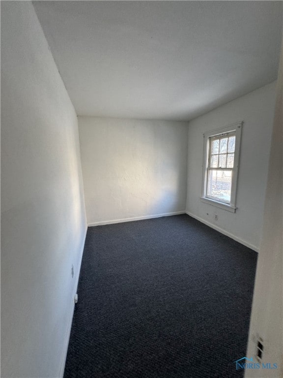 spare room with dark carpet