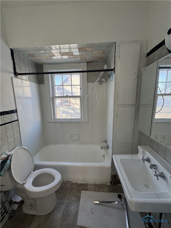 full bathroom featuring tiled shower / bath, sink, tile walls, and toilet