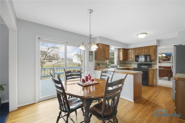 dining space featuring sink, an inviting chandelier, and light hardwood / wood-style floors