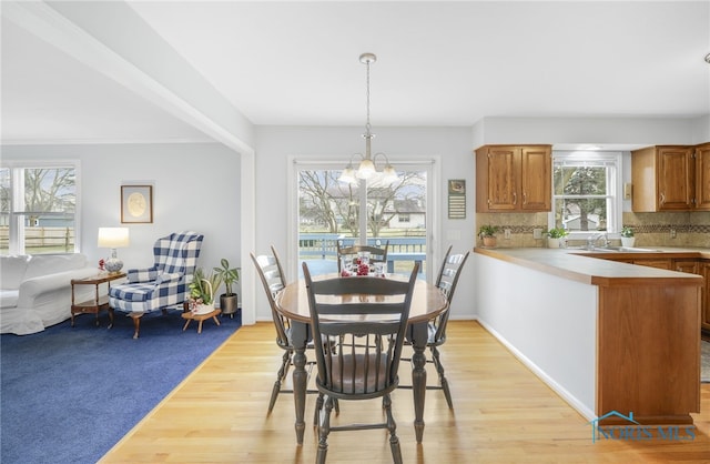 dining area with sink, light hardwood / wood-style flooring, and a notable chandelier