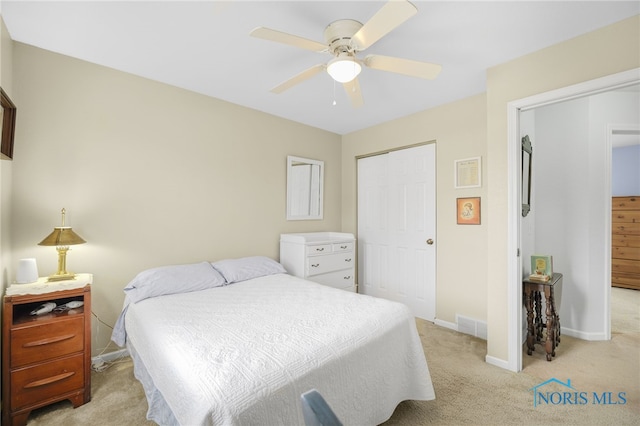 bedroom featuring light colored carpet, a closet, and ceiling fan