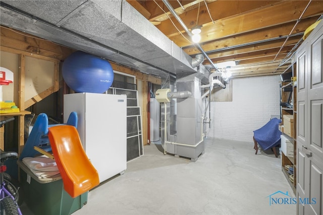 basement with white refrigerator, brick wall, and heating unit