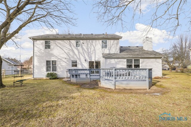 rear view of property featuring a wooden deck and a lawn