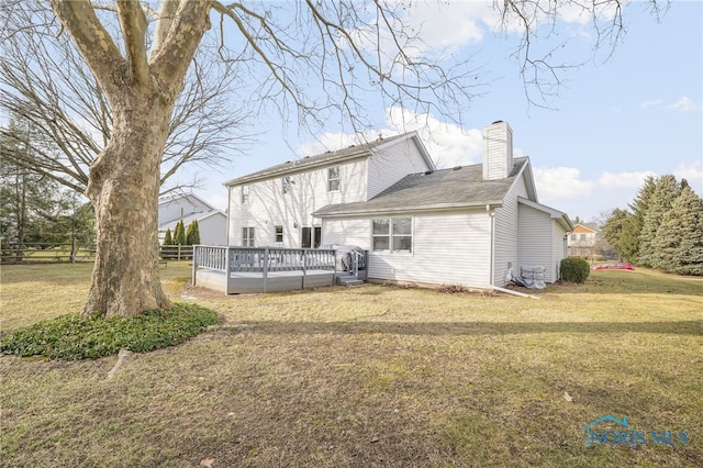 back of property with a wooden deck and a lawn