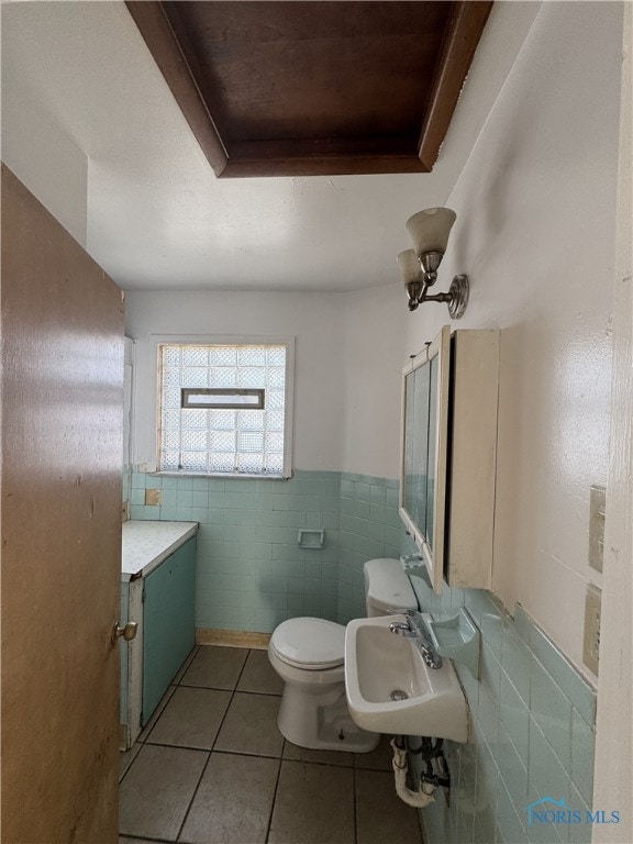 bathroom with sink, tile patterned flooring, tile walls, a raised ceiling, and toilet