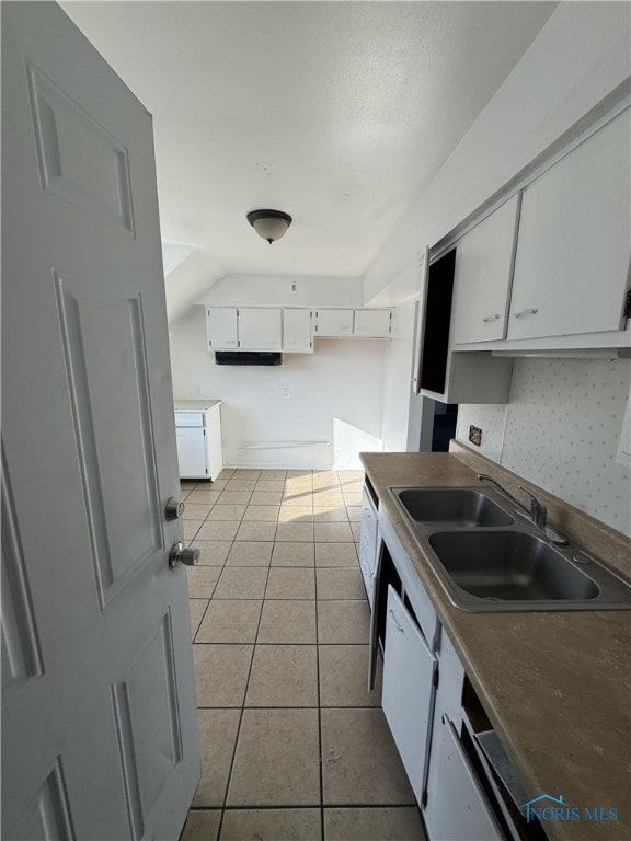 kitchen with white cabinetry, backsplash, sink, and light tile patterned floors