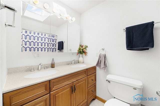 bathroom with a shower with curtain, vanity, toilet, and a skylight