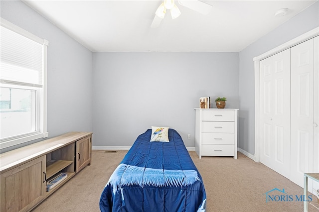 bedroom with ceiling fan, a closet, and light carpet