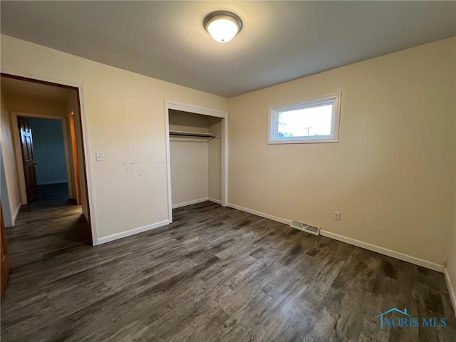 unfurnished bedroom with dark wood-type flooring and a closet